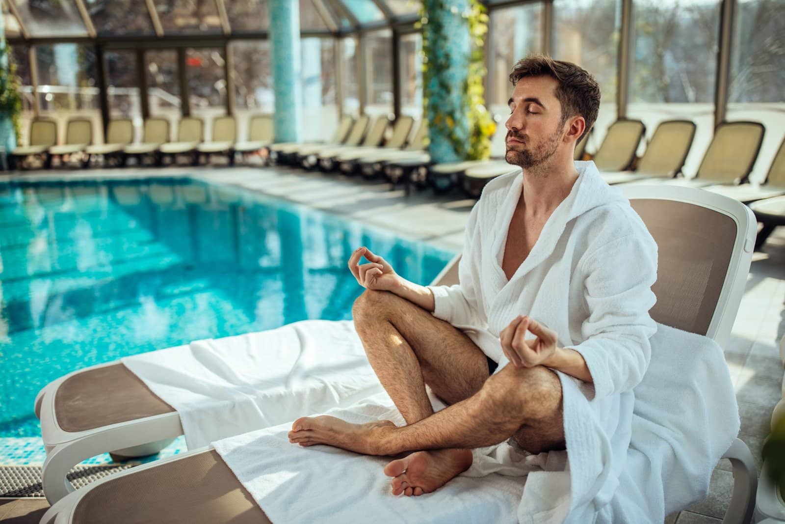 Man meditating by a pool